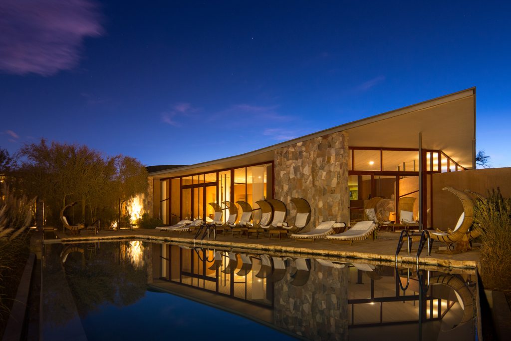 Pool with hotel restaurant in the background at night