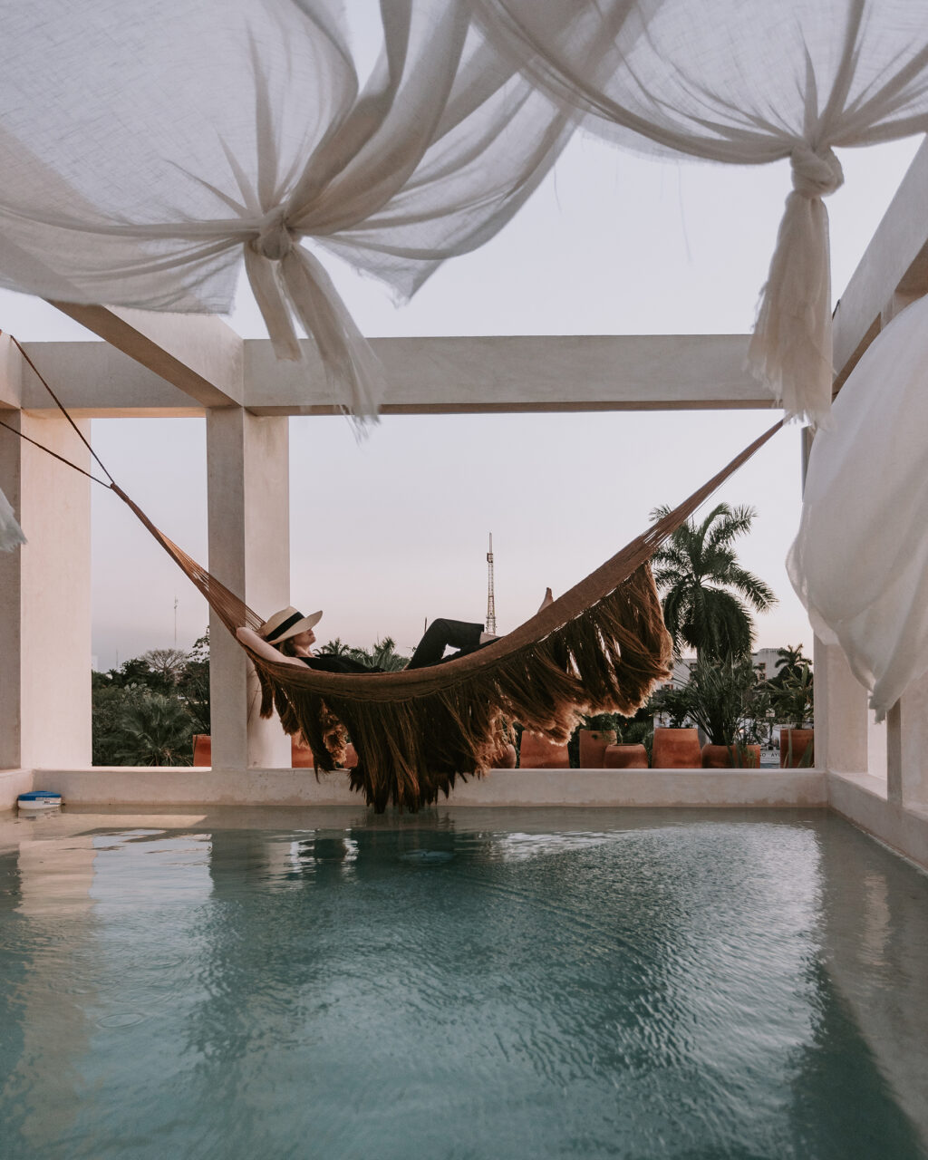 A woman laying on a hammock above a pool