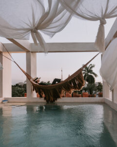 A woman laying on a hammock above a pool