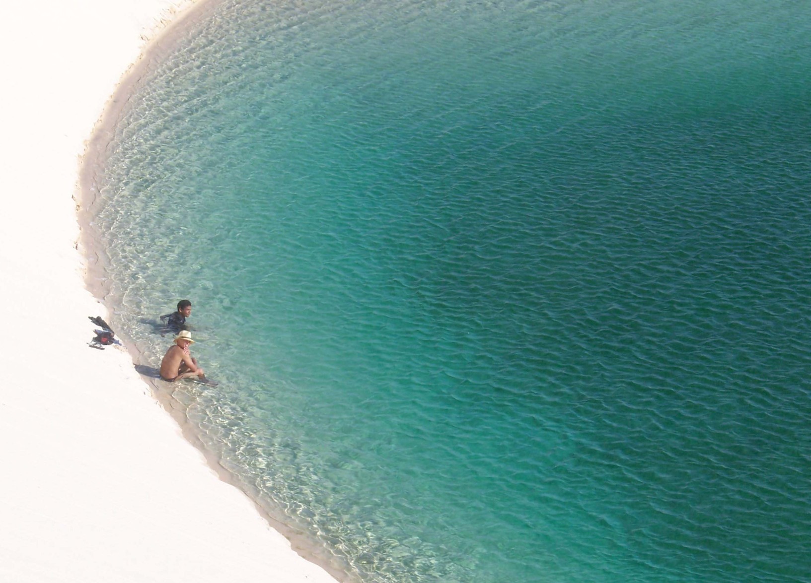 Two children relaxing on a beach with crystal blue water